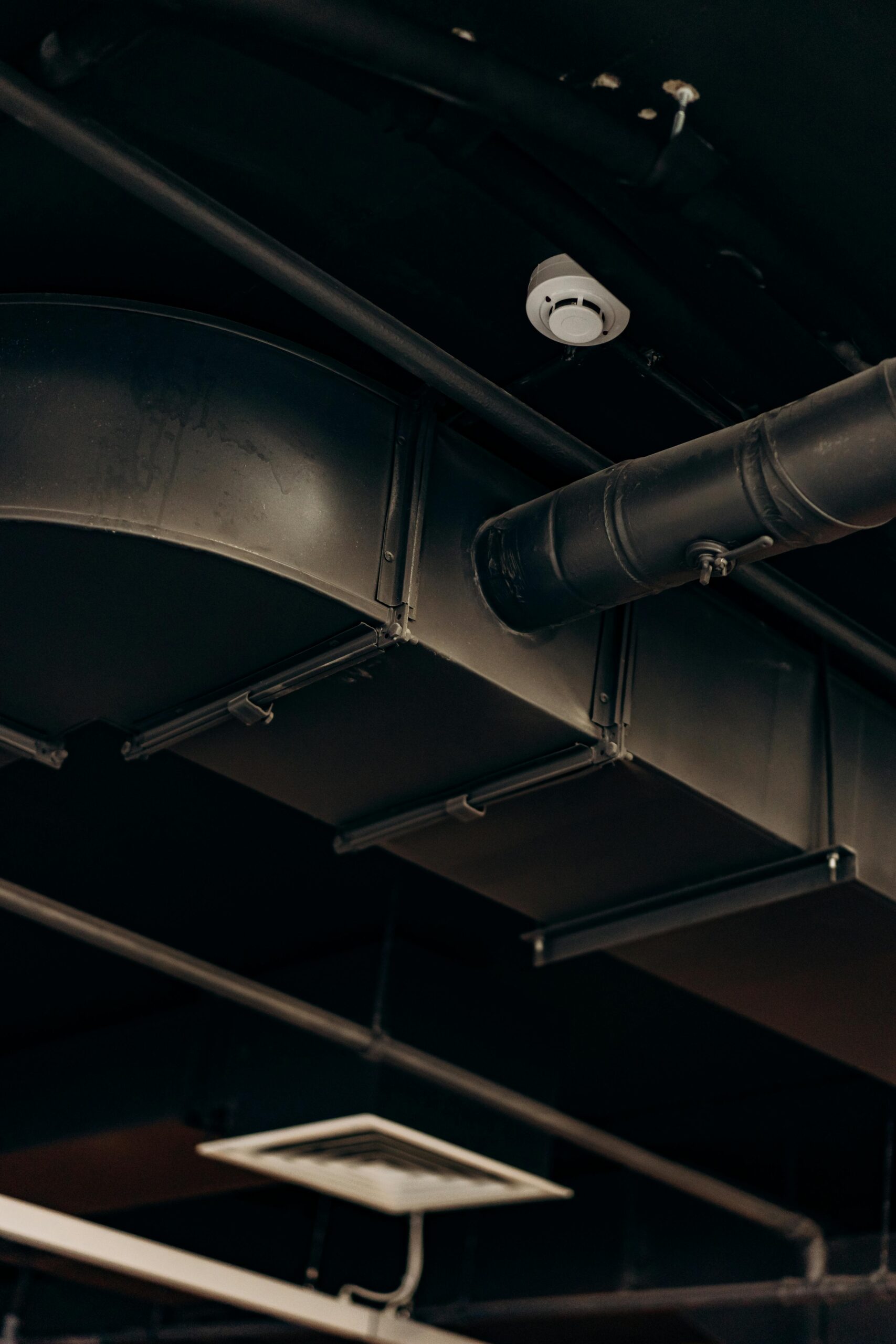 Detailed view of industrial air ducts on a ceiling, showcasing modern urban design.