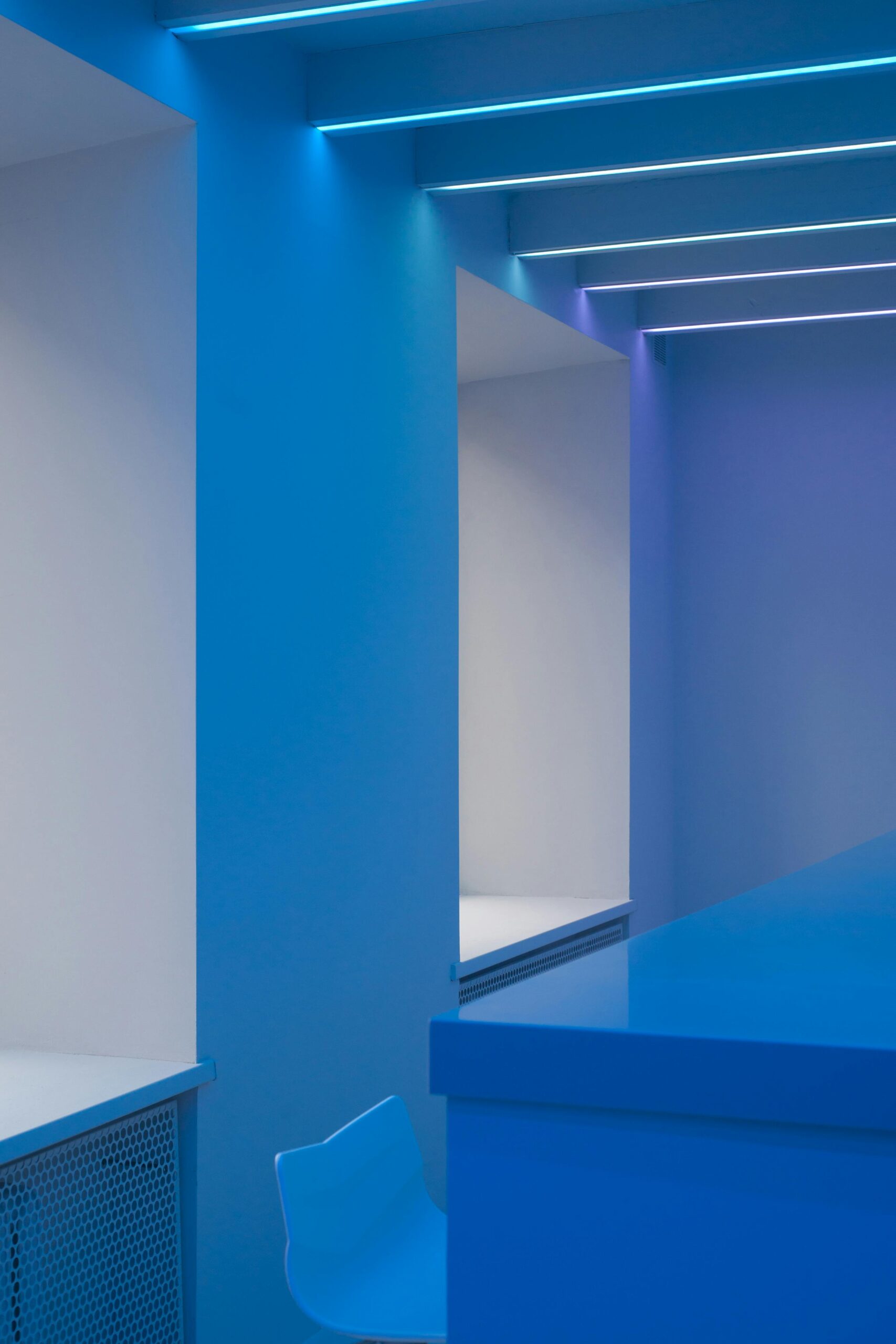 Contemporary blue room featuring minimalistic design with neon ceiling lights.