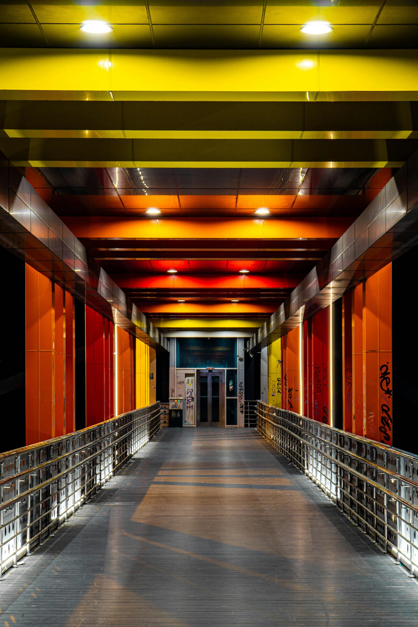 Colorful illuminated pedestrian bridge with modern design at night.