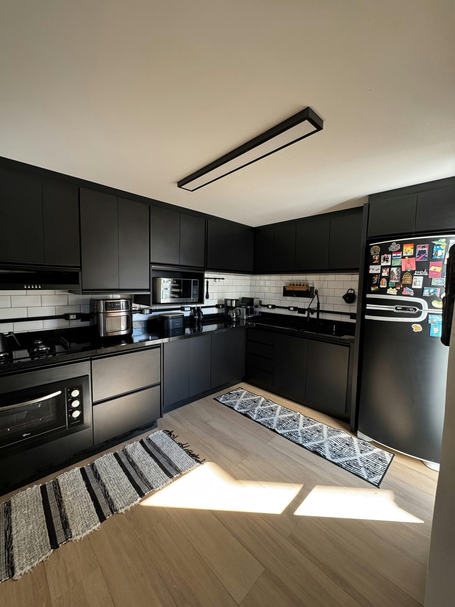 Sleek modern kitchen with black cabinets and natural light creating a warm ambiance.